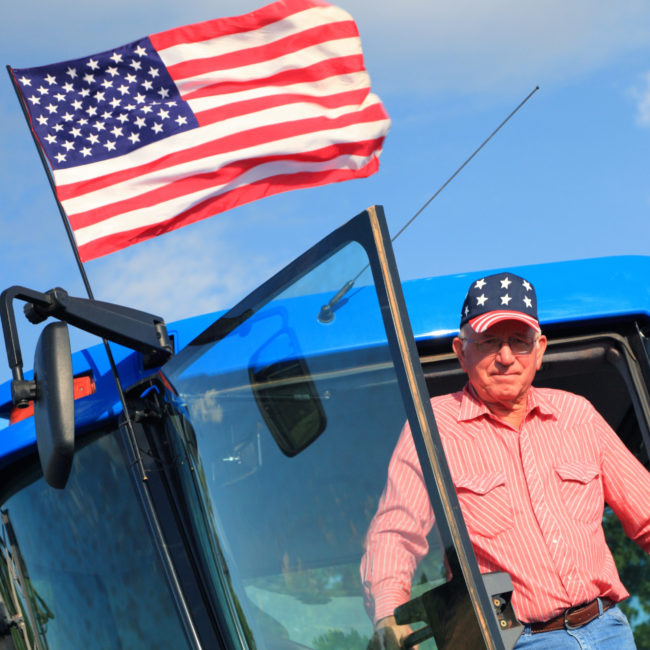Agriculture: Patriotic American Farmer on Tractor with Flag