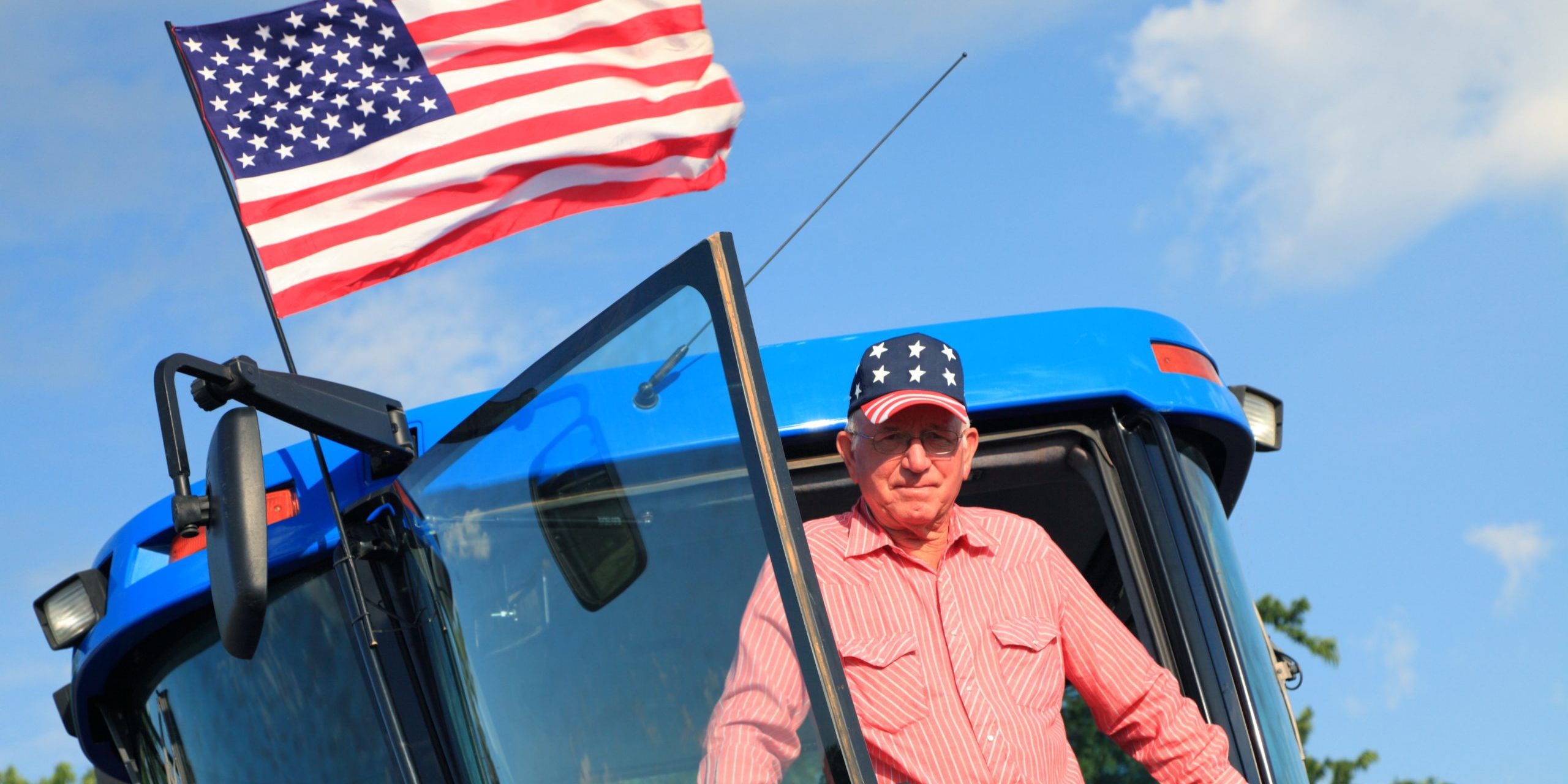 Agriculture: Patriotic American Farmer on Tractor with Flag