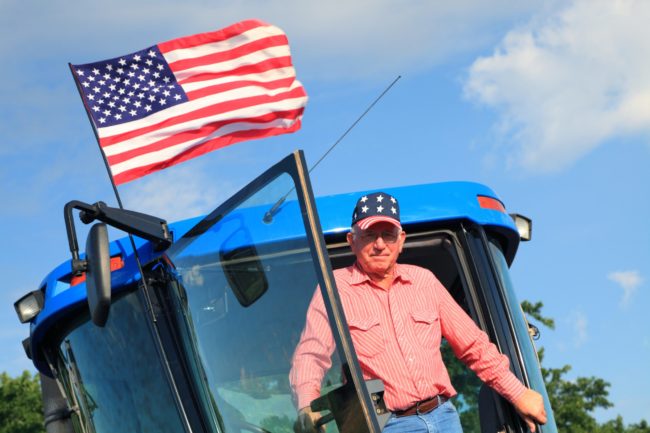 Agriculture: Patriotic American Farmer on Tractor with Flag